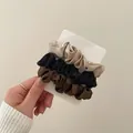 Close-up of silk satin scrunchies in beige, black, and brown on a display card - Khaki Brown Black