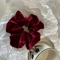 Close-up of a burgundy velvet scrunchie featuring a soft texture and luxurious glossy finish - Burgundy