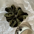 Detail view of a large forest green velvet scrunchie with soft pleated texture and retro style - Green