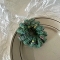 Detail of plush fuzzy hair tie in dark green with colorful dots on a ceramic plate - Green (Plain Loop)