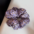 Détail d'un chouchou en satin violet à imprimé léopard avec un design élastique plissé - Violet