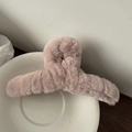 Detailopname van een roze pluche haarklem met zacht imitatiebont op een wit bord - Lichtroze