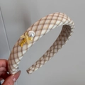 Detail of yellow checkered headband featuring a faux pearl, bow, and handmade charm - Vitality Beige - Headband