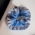 Detailed view of blue fabric scrunchie with checkered pleated edges and orange stitching - Ruffled Scrunchie