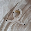 Detail der gedrehten Haarklammer mit schwarzen Punkten auf cremefarbenem Acetat-Material - Kreuzschleifen-Stil