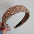 Detailaufnahme des handgefertigten Etiketts an einem braun karierten Haarband - Braun