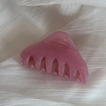 Detailed view of a pink translucent triangular hair claw clip on white textured fabric - Pink