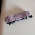 Detailed macro view of purple satin bow hair clip with black plastic banana clip structure - Purple