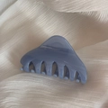 Détail d'une pince à cheveux triangulaire en résine bleu clair sur mousseline beige - Bleu