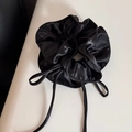 Detail of a black satin scrunchie with long ribbons showing silky smooth texture - Black