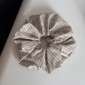 Close-up of a plaid fabric scrunchie with a hand made label and detailed texture - Purple Rice Grid Scrunchie