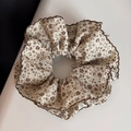 Gros plan sur un chouchou en coton beige à fleurs avec bords ondulés marron foncé - Style Taille Cintré Bord Ondulé / Fleur Beige