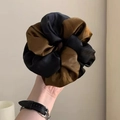 Gros plan d'un chouchou en satin bicolore avec texture soie et design plissé surdimensionné - Café Noir