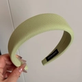 Detail of light green ribbed fabric headband with a black handmade woven label - Green
