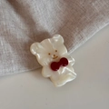 Dettaglio del fermaglio a orsetto perlato con fiocco rosso su tessuto - Bianco Crema
