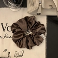 Vista dettagliata dell'elastico in raso color cioccolato con etichetta logo premium - Marrone