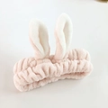 Gros plan d'un bandeau en peluche douce avec oreilles de lapin pour le maquillage - Rose Clair