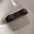 Detailed view of a dark grey bow hair comb with 12-tooth metal clip on ceramic background - Gray