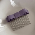 Detailed close-up of a purple fabric bow hair comb with ten silver metal teeth - Purple