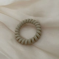 Minimalistische mat beige spiraalvormige haarelastiek op luxe zijden achtergrond - Beige Khaki