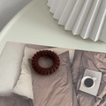 Primo piano di un elastico per capelli a spirale marrone in velluto e plastica elastica - Cachi