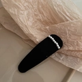 Vista dettagliata di un fermaglio per capelli nero in tessuto con eleganti perline bianche - Goccia d'acqua nera