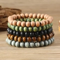 Set of five bohemian wood bead bracelets in assorted matte colors on a wooden surface - Multi-color / Multicolor