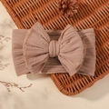 Elastic jacquard baby headband with a large bow in dusty rose color on a basket - Dusty Pink