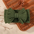 Deep green ribbed knit baby headband featuring a large bow on a vintage basket - Dark Green