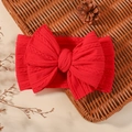 Elastic red baby headband with a large knit bow design on a woven basket background - Red
