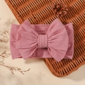 Pink elastic wide baby headband featuring a large bow and ribbed texture on a basket - Lotus Pink