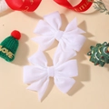 Gros plan d'une paire de nœuds à cheveux en velours blanc avec décor de Noël festif - Blanc