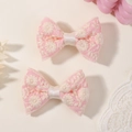 Detail van roze geborduurde kanten haarstrikken met delicate witte bloemmotieven - Roze