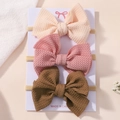 Detailed view of three baby bow headbands with waffle texture on white display card - Style 3B