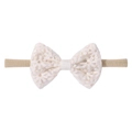Close-up of baby nylon headband with white lace bow and delicate daisy embroidery - Milky White