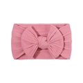 Detail of pink knitted baby headband featuring a large bow and elastic ribbed texture - Pink