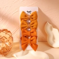 Detail view of four-piece bow hair clip set in orange and yellow fabrics on display card - Bright Orange And Ginger Yellow Style (6)