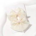Détail de deux barrettes à nœud en organza blanc cassé avec ruban délicat sur carte de vente - Crème