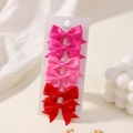 Détail d'un lot de six barrettes à nœuds en satin rouge et rose sur une carte de présentation - Série Rouge/Rose (6B)