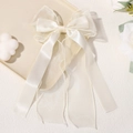Elegant cream chiffon bow hair clip with long ribbons on a decorative tray - Off White