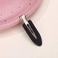 Detail of matte black creaseless hair clip with metal base on pink decorative plate - Black