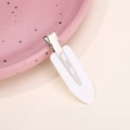 Detail view of a minimalist white hair clip on a pink decorative plate for hairstyling - White