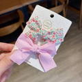 Detail view of handmade floral and pink bow hair clips on display card with white dots - Pink
