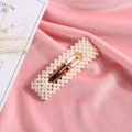 Barrette rectangulaire dorée ornée de perles blanches sur fond de velours rose - Style D Or