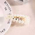 Barrette en métal doré avec des perles blanches disposées sur un tissu beige texturé - Type F Or
