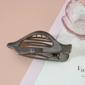 Détail d'une pince à cheveux gris foncé translucide avec design ajouré sur fond coloré - Gris foncé