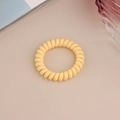 Detailed view of a light yellow matte spiral hair tie on a decorative aesthetic background - Matte-Yellow