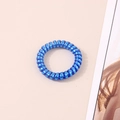 Macro shot of a flexible royal blue spiral hair tie on a minimalist background - Metallic Blue