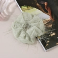 Detailed texture of light green mesh scrunchie with sparkling fringe on flat surface - Green