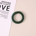 Elastic dark green spiral telephone wire hair tie on a minimalist beige background - Glossy Dark Green